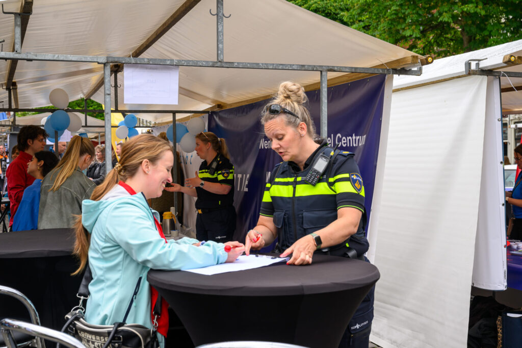 Politieagente in gesprek met een bezoeker bij de politiestand op de banenmarkt
