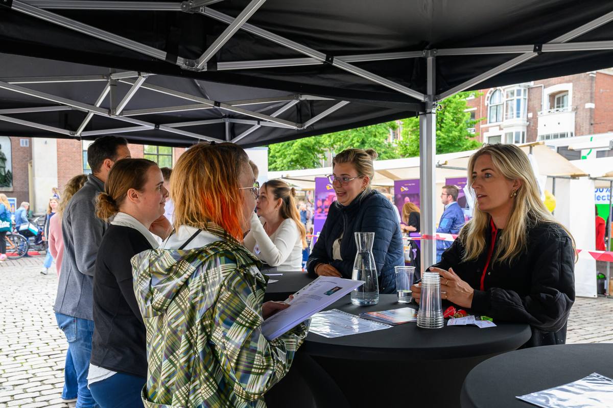 Bezoekers in gesprek met werkgevers aan statafels tijdens het speednetwerken op De Banenmarkt