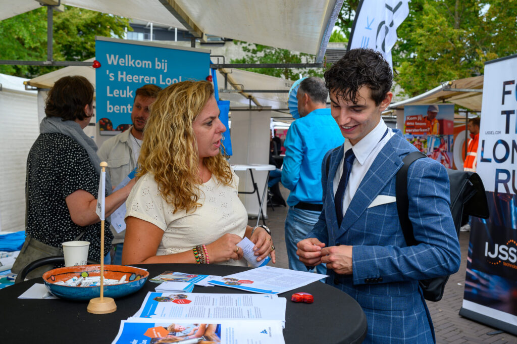 Bezoeker in gesprek met een werkgever bij een kraam op De Banenmarkt Emmen