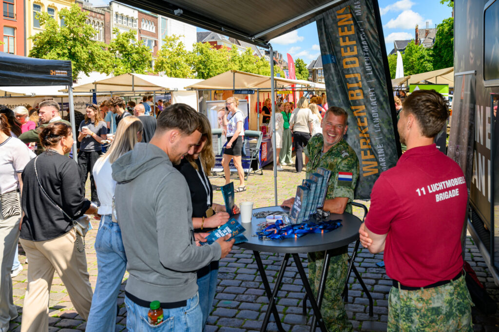 Bezoekers in gesprek bij de stand van Defensie op De Banenmarkt