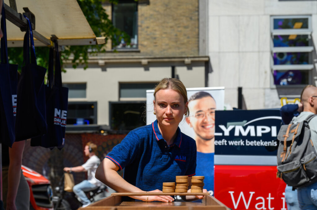 Bezoekers in gesprek met werkgevers bij de kramen op De Banenmarkt