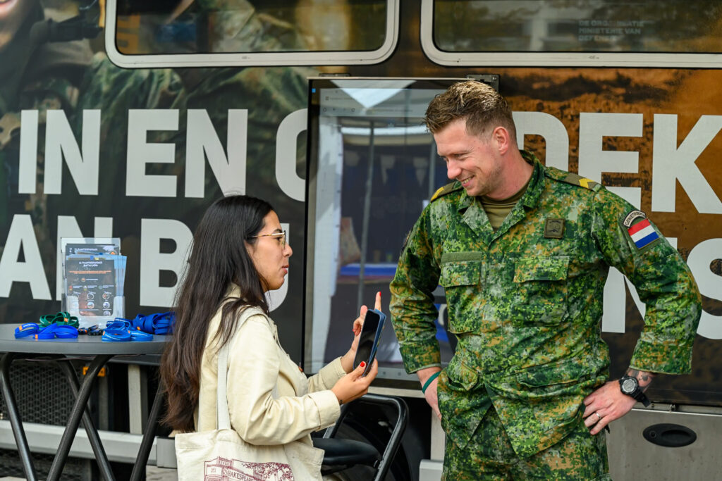 Bezoeker in gesprek met een medewerker van Defensie bij de stand op De Banenmarkt Groningen