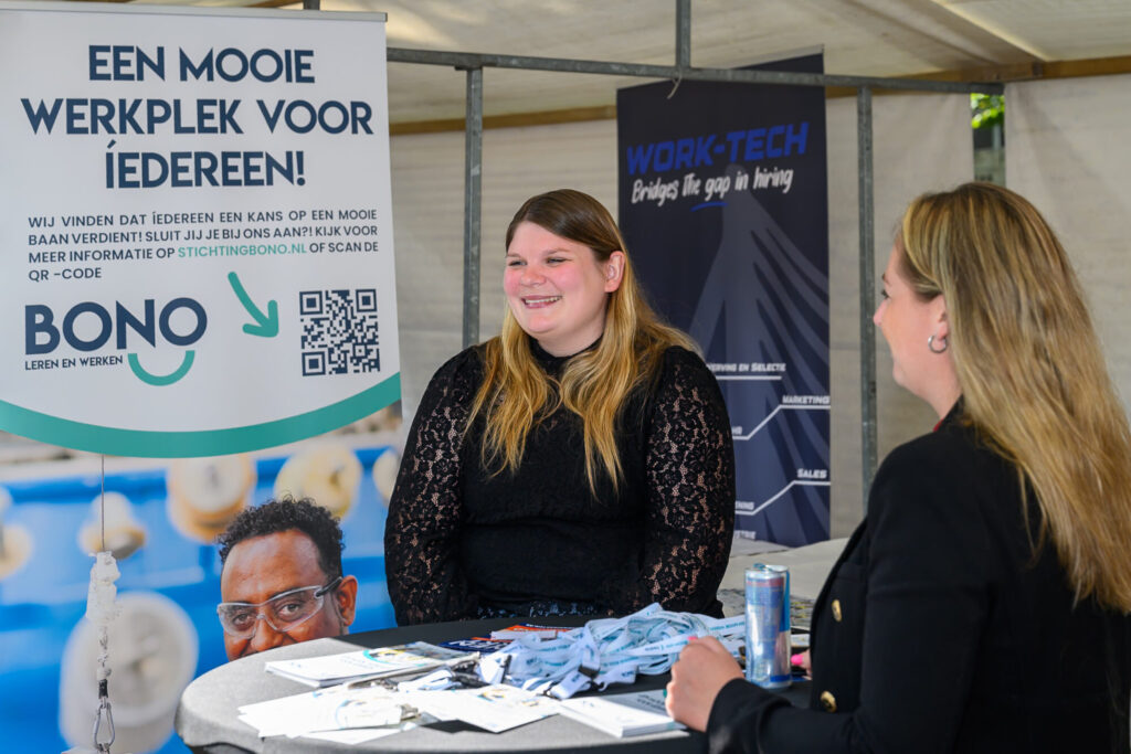 Bezoeker in gesprek met een opleider bij de stand van BONO Leren en Werken op De Banenmarkt Emmen
