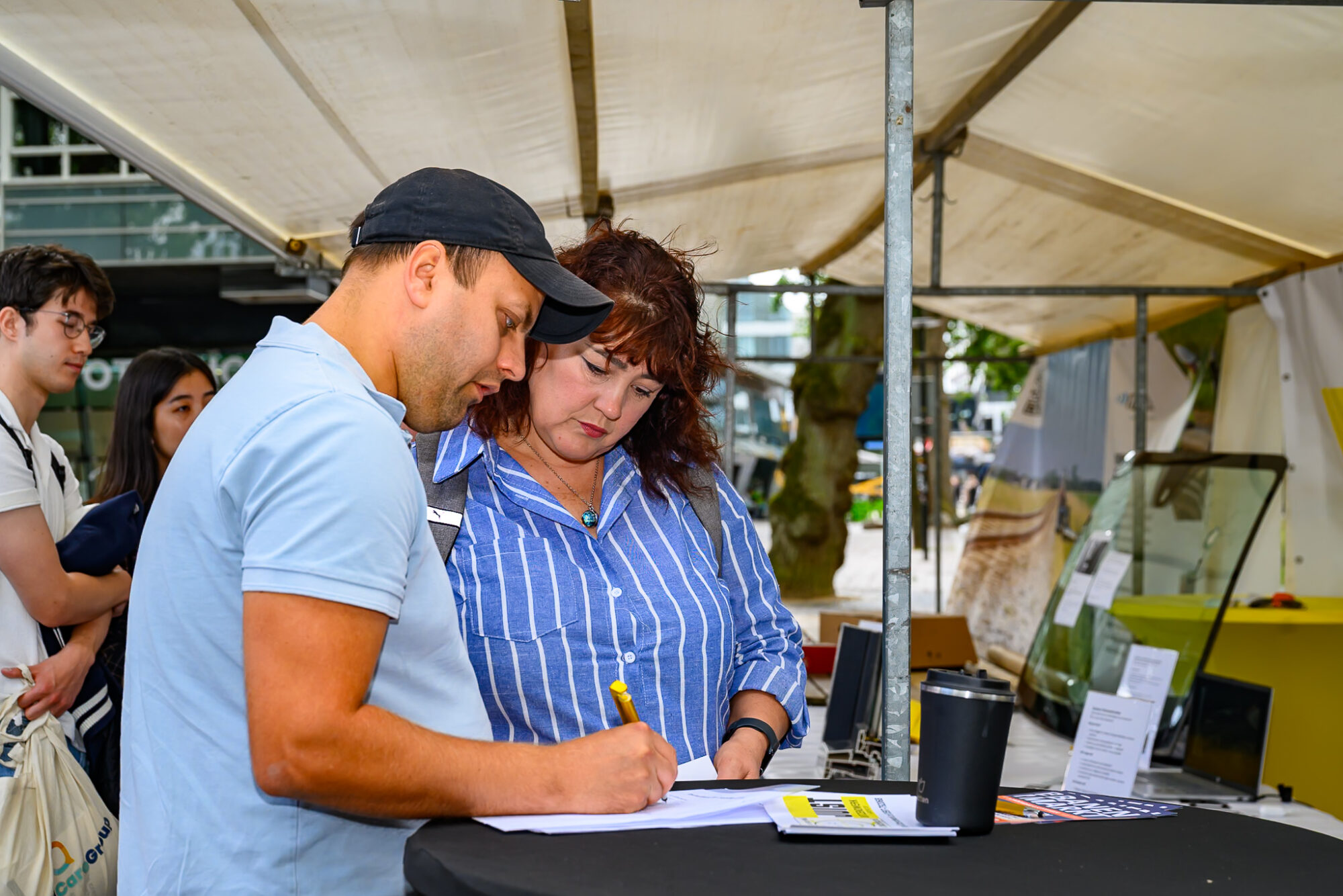 Bezoekers vullen samen een formulier in bij een stand op De Banenmarkt Emmen