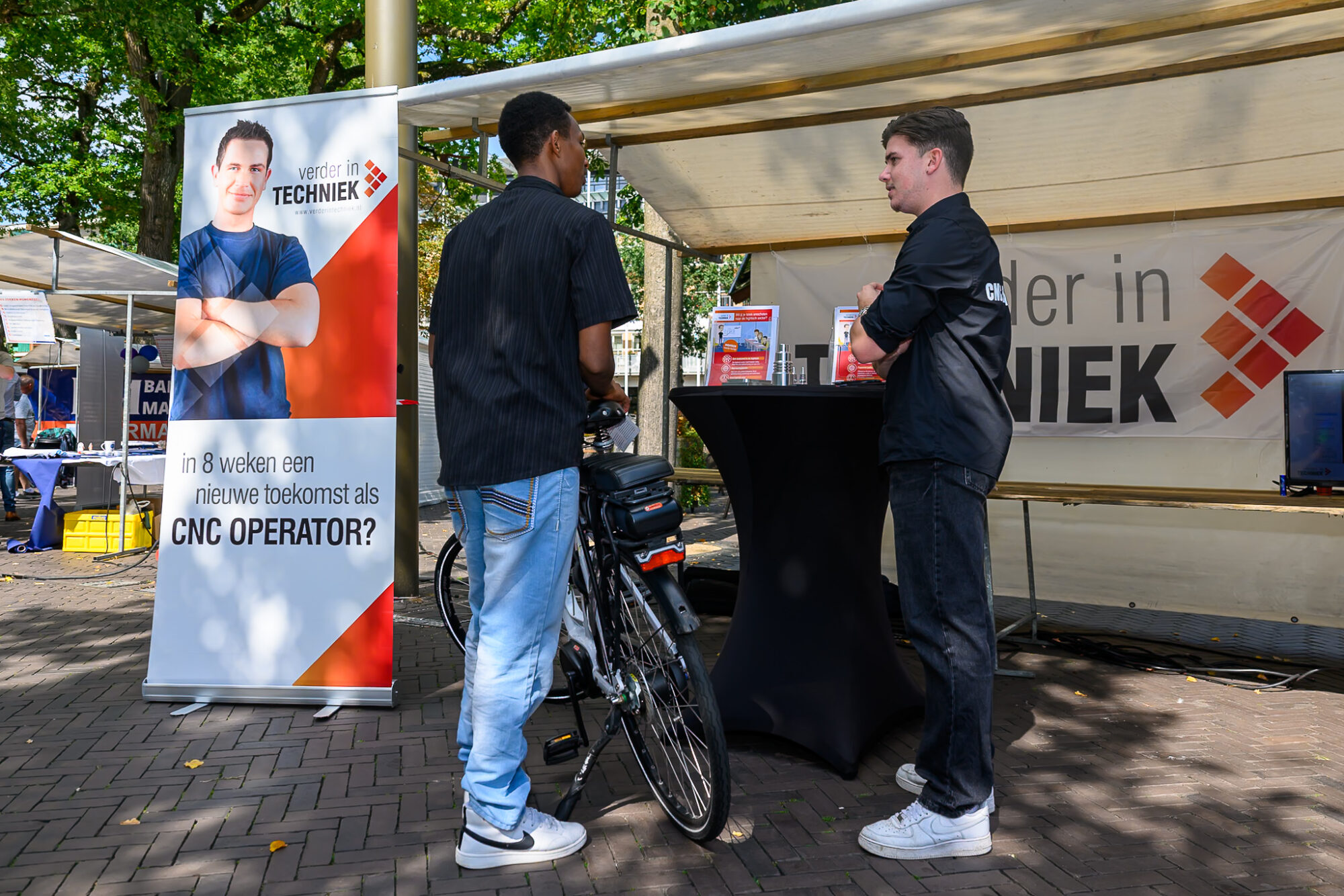 Jonge bezoeker in gesprek met een medewerker bij de stand van Verder in Techniek op De Banenmarkt Emmen