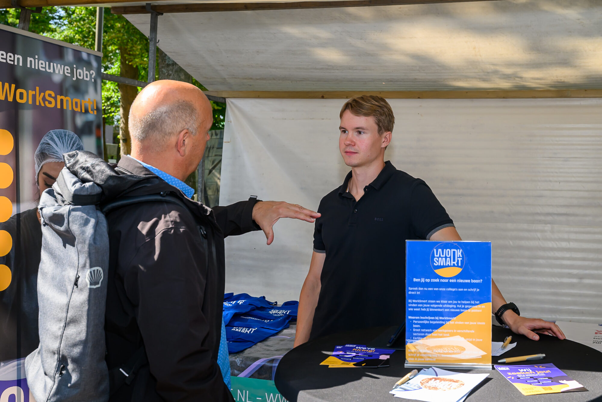 Bezoeker in gesprek met een medewerker van uitzendbureau WorkSmart op De Banenmarkt Emmen